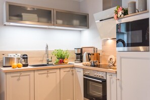 A modern kitchen with a built-in oven, a coffee maker, and a sink. - Barther Strasse 10 "Seeschwalbe" - comfortable semi-detached house "Haus (Zingst)