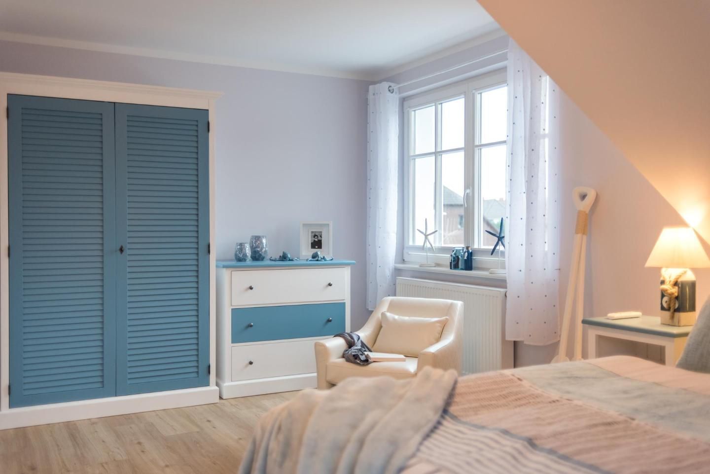 A bedroom with a bed, a dresser, a chair, a window, and a radiator.