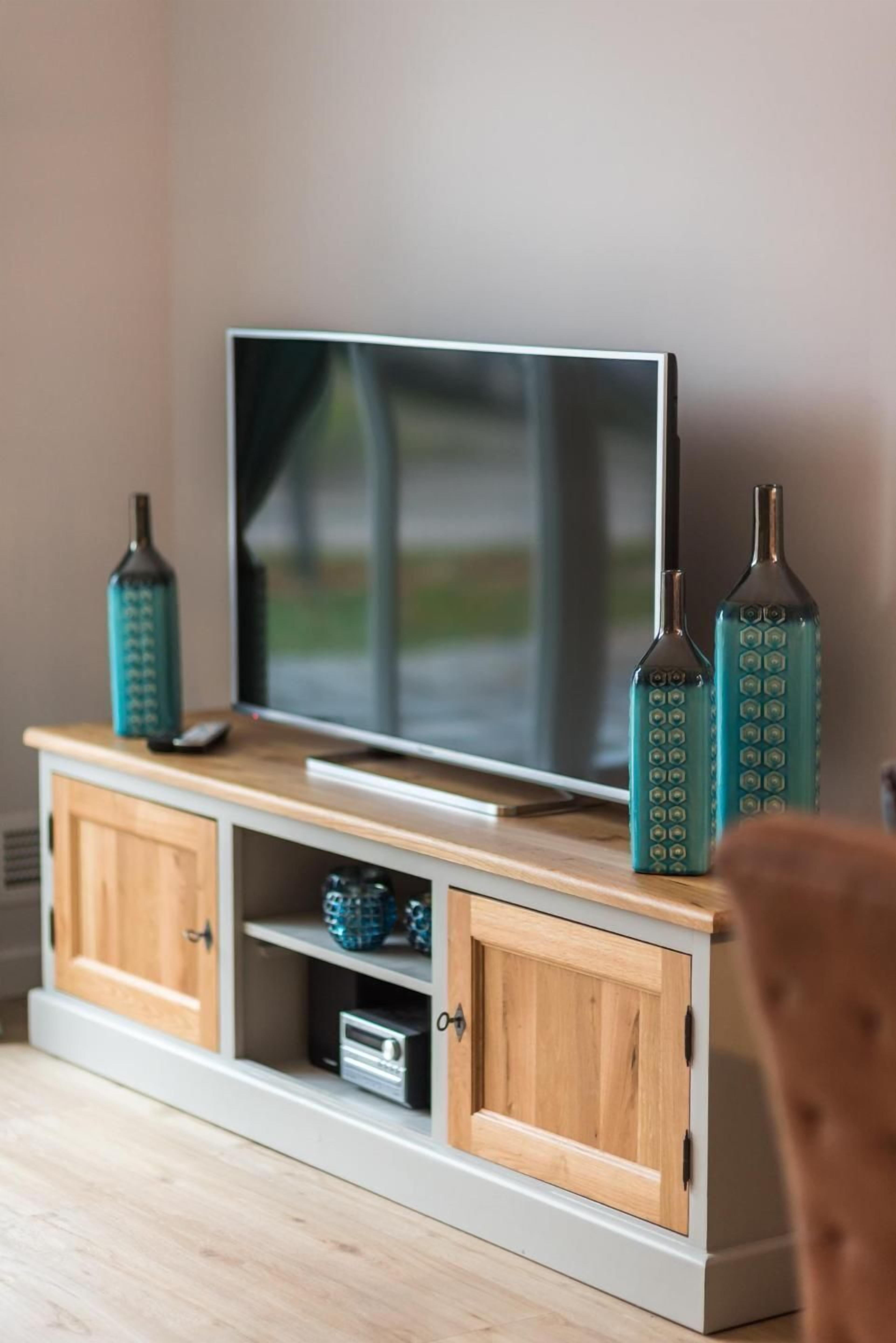 Una televisione su un supporto in legno con due bottiglie decorative.