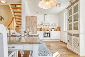 Eine moderne Küche mit weißen Schränken, einem Holzespeisetisch und einem eingebauten Backofen.