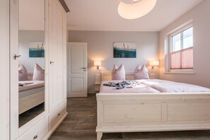 Ein Schlafzimmer mit einem großen Bett, einem Kleiderschrank, einer Tür, einem Fenster und zwei Wandleuchten.