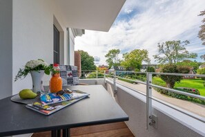 Een balkon met een tafel, een fles, een glas, een peer en een tijdschrift.