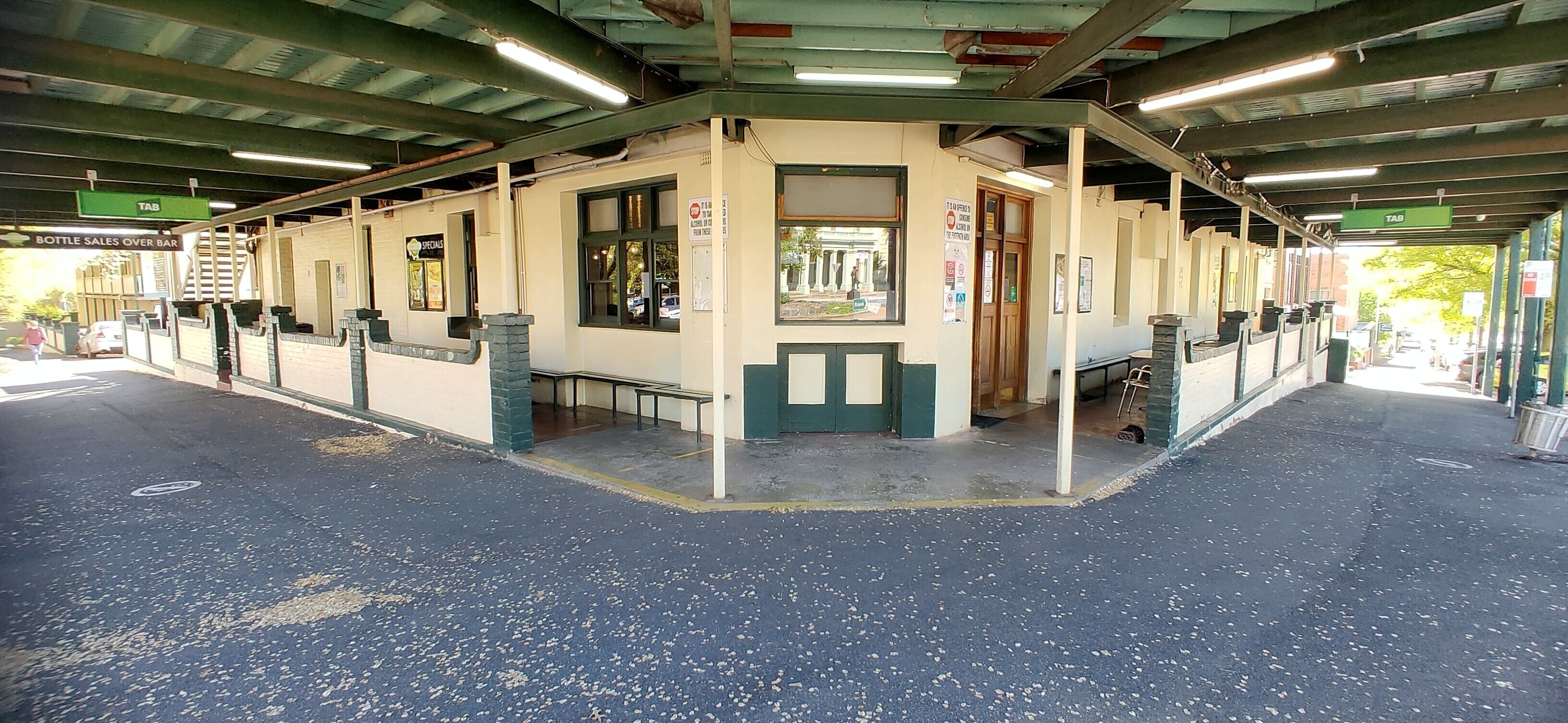 A covered outdoor area with a kiosk labeled "Bottles Sales Over Bar" and a "Beers" sign.