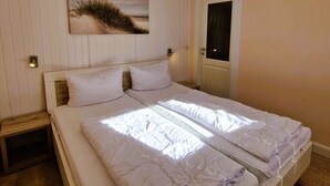 Un dormitorio con cama, mesita de noche, puerta y una obra de arte colgada en la pared.