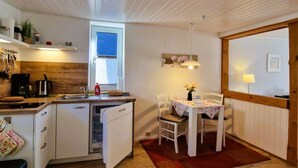 Cocina compacta con pileta, cocina y alacenas. Hay un comedor con mesa y sillas.