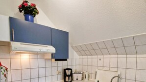 Eine kompakte Küche mit Herd, Backofen, Spüle und blauen Schränken.