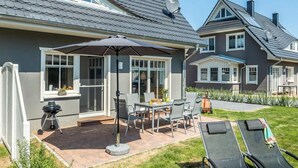 Una proprietà residenziale con un patio che include un tavolo, sedie, un barbecue e un'area relax coperta con ombrellone.