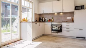 Una cucina moderna con mobili bianchi, forno integrato e microonde.