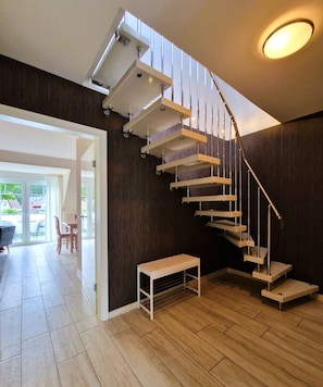 A modern interior with a spiral staircase, a bench, and a view of the outside.