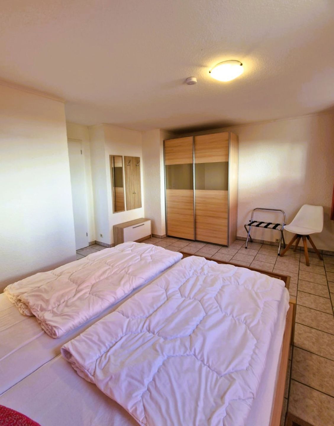 Ein Schlafzimmer mit zwei Betten, einem Kleiderschrank, einem Sessel und einem kleinen Tisch.