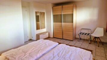 Ein Schlafzimmer mit zwei Betten, einem Kleiderschrank, einem Sessel und einem kleinen Tisch.