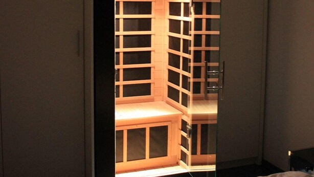A bedroom with a bed, a wardrobe, and a built-in shelving unit with a mirror.
