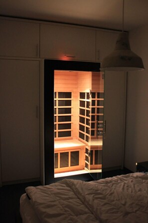 A bedroom with a bed, a wardrobe, and a built-in shelving unit with a mirror.