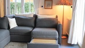 A modern living room with a grey sectional sofa, a small ottoman, and a floor lamp.
