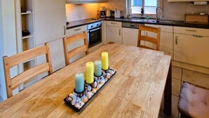 Une cuisine moderne avec des meubles en bois, un îlot central agrémenté de bougies et des luminaires suspendus.