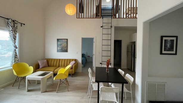 Un appartement moderne comprenant un coin repas, un canapé et un escalier menant à un niveau supérieur.