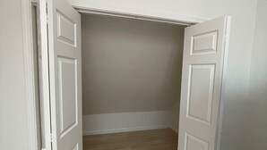 Une pièce avec un plafond en pente, un plancher en bois et des murs blancs.