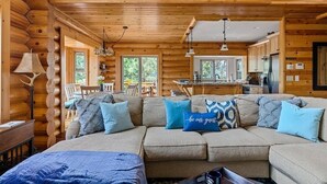 L’intérieur d’une cabane en rondins, avec un salon accueillant, une table à manger et une cuisine.