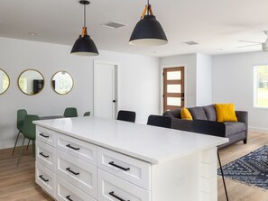 Relax in this stylish living space with a central island, grey sofa, and green chairs.