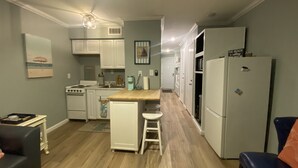 A compact kitchen with white cabinets, a wooden countertop, and a refrigerator. - Just Beachy (Corpus Christi)