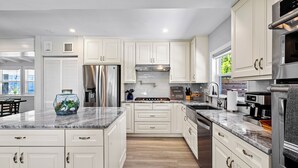 Una cocina moderna con armarios blancos, electrodomésticos de acero inoxidable y encimera de mármol.