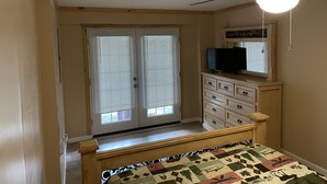 Un dormitorio con cama, cómoda, televisor y ventilador de techo.