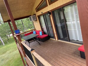 A covered outdoor deck with a red sofa, a table, and a pergola. - Relax by the lake (Lake Ariel)