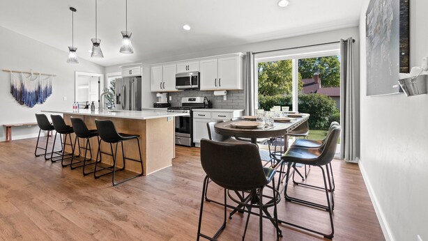 A modern kitchen with white cabinets, a central island, and bar stools.