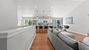 A modern kitchen with white cabinets, a central island, and pendant lighting.