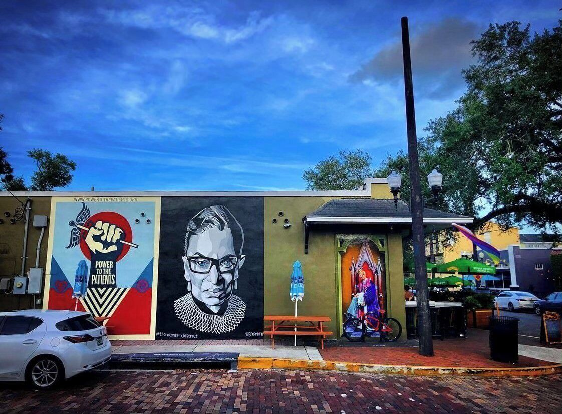 A mural on a building with a bench and a bicycle.