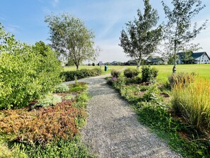 Stroll through the beautifully maintained garden pathway, lined with lush plants and shrubs, leading to a serene residential area.