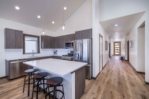 Enjoy cooking in this well-equipped kitchen with a large island, stainless steel appliances, and dark cabinetry.