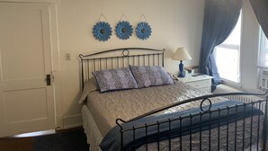 Una camera da letto con un letto, un comodino, una lampada e due decorazioni a parete.