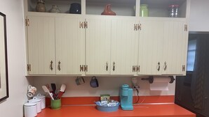 Una cucina con mobili bianchi, un piano di lavoro rosso e diversi utensili da cucina.