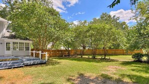 A backyard with a wooden deck, a small fire pit, and a wooden fence. - Plantation Styled Home with Sunroom and Large Deck/Yard (Augusta)