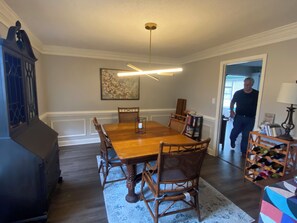 Ein Esszimmer mit Holztisch und -stühlen, einer Kandelaber und einem Bücherregal.