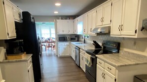 A modern kitchen with white cabinets, a black refrigerator, and a stainless steel oven. - Plantation Styled Home with Sunroom and Large Deck/Yard (Augusta)