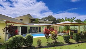 A modern two-story house with a swimming pool, surrounded by well-maintained gardens and tropical plants. - Comfy and Convenient Home Minutes from Beach National Park (Uvita)