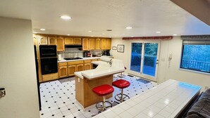 A kitchen with wooden cabinets, a white countertop, a built-in oven, and a window overlooking a deck. - Ray of Moon-Spacious getaway in PML near Yosemite + Kayaks + backup power (Groveland)