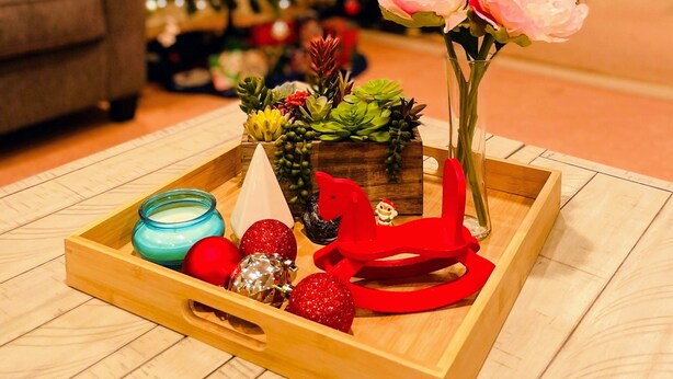 A wooden tray with a candle, red and silver ornaments, and a pink flower in a vase, placed on a wooden floor with a Christmas tree in the background. - Ray of Moon-Spacious getaway in PML near Yosemite + Kayaks + backup power (Groveland)