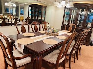 A dining room with a wooden table set for six, surrounded by matching chairs.