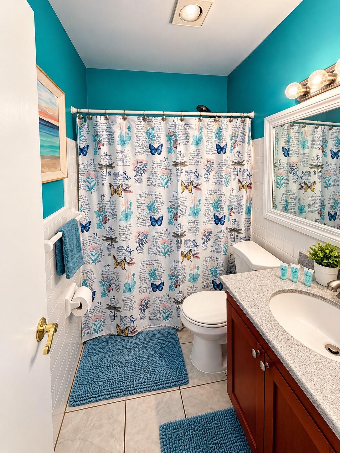 A bathroom with a blue shower curtain, white toilet, and a sink with toiletries.
