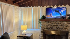 A cozy living room with a fireplace, comfortable seating, and a television on a stone wall.