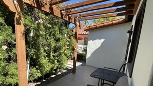 Un espace extérieur aménagé en terrasse, avec une pergola, une table et deux chaises.