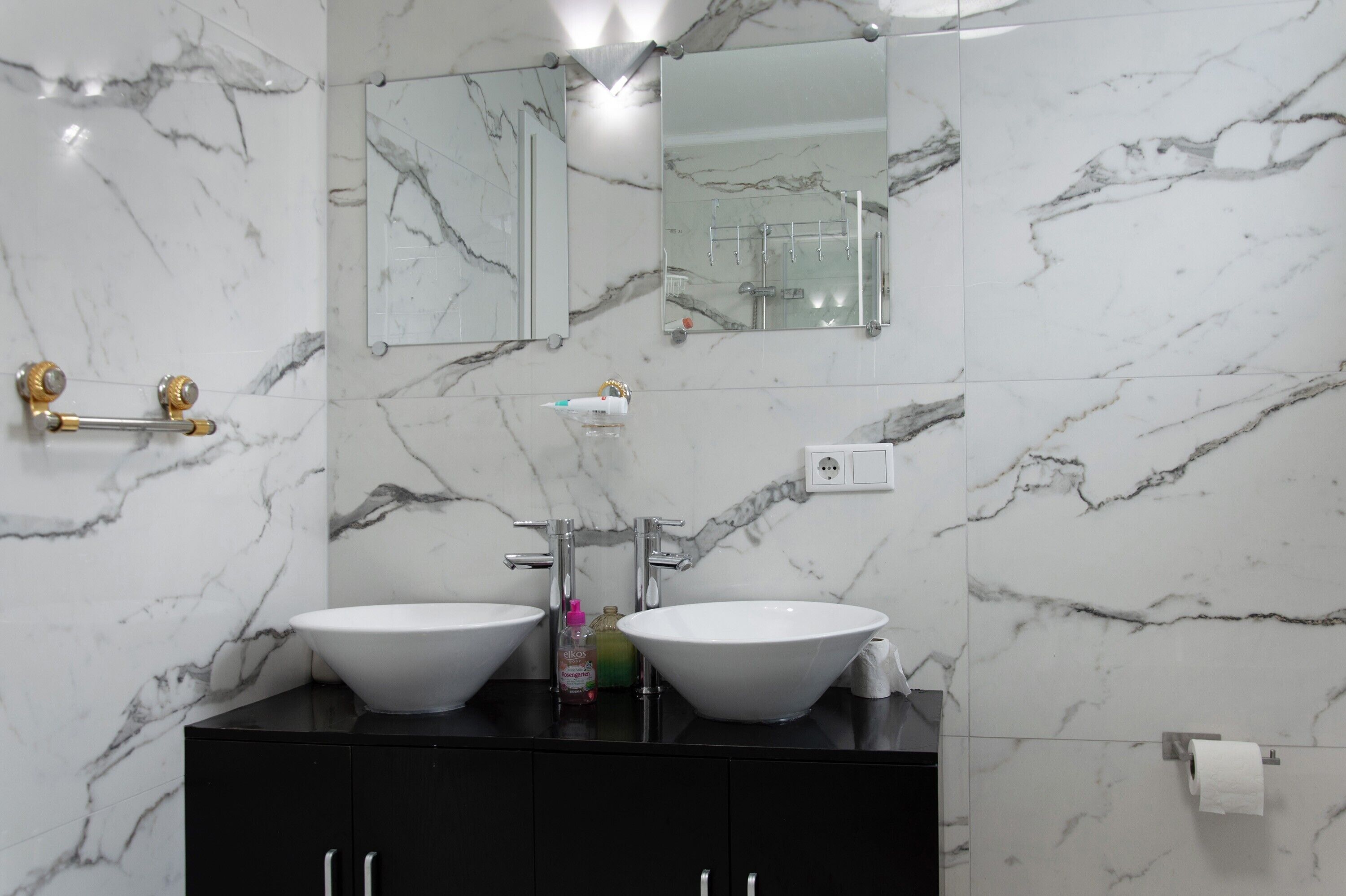 Un bagno con due lavabi, uno specchio e un mobile contenitore nero.