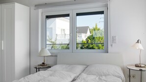 A bedroom with a bed, a window, a nightstand, and a lamp.