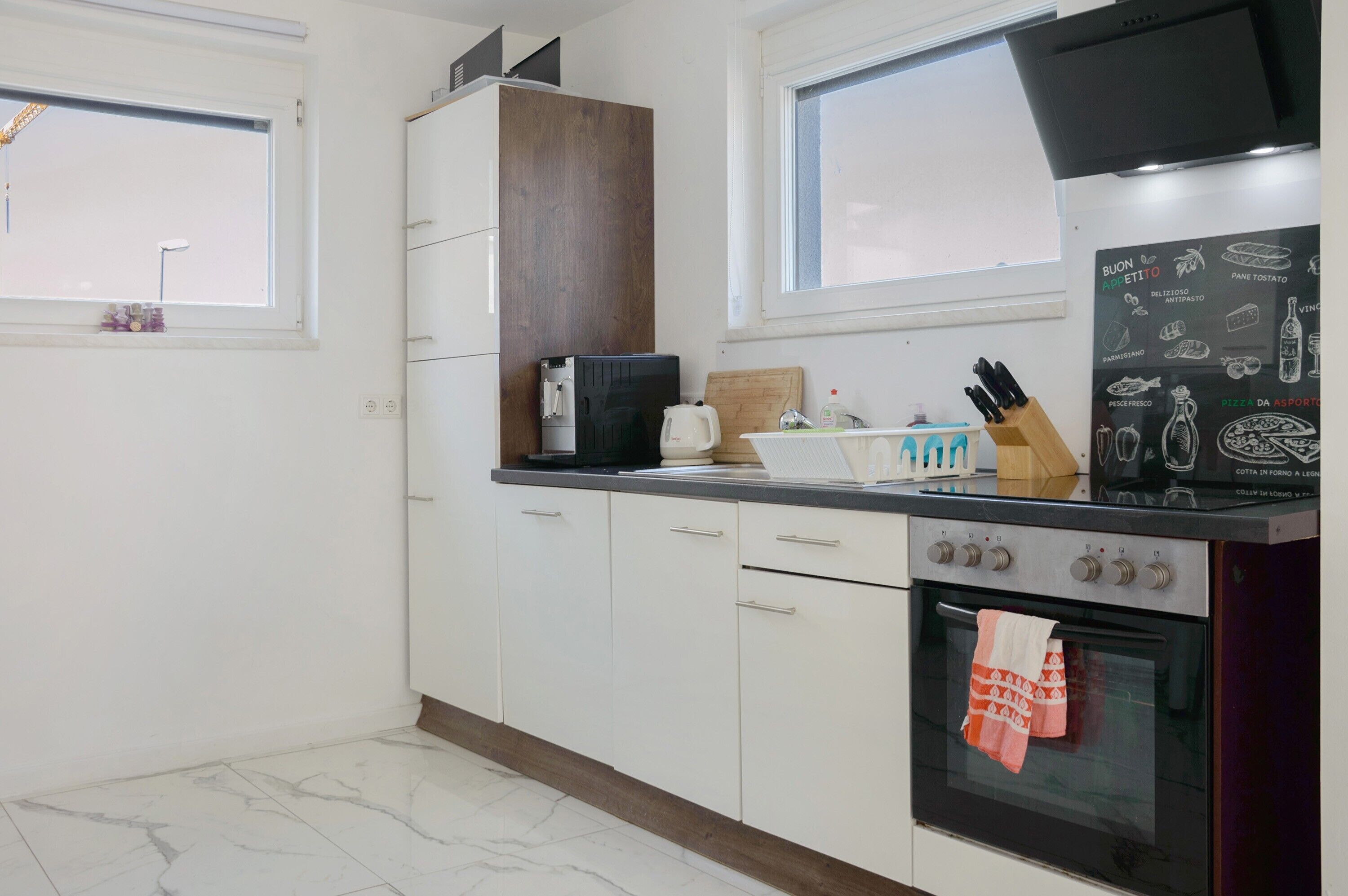 Una cocina con armarios blancos, una cafetera, un tostador, un bloque de cuchillos y una estufa.