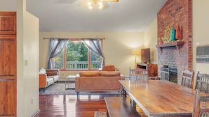 A spacious living room with a wooden dining table, a sofa, and a fireplace.