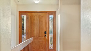 A wooden front door with a glass panel, a wooden handrail, and a bench in front.