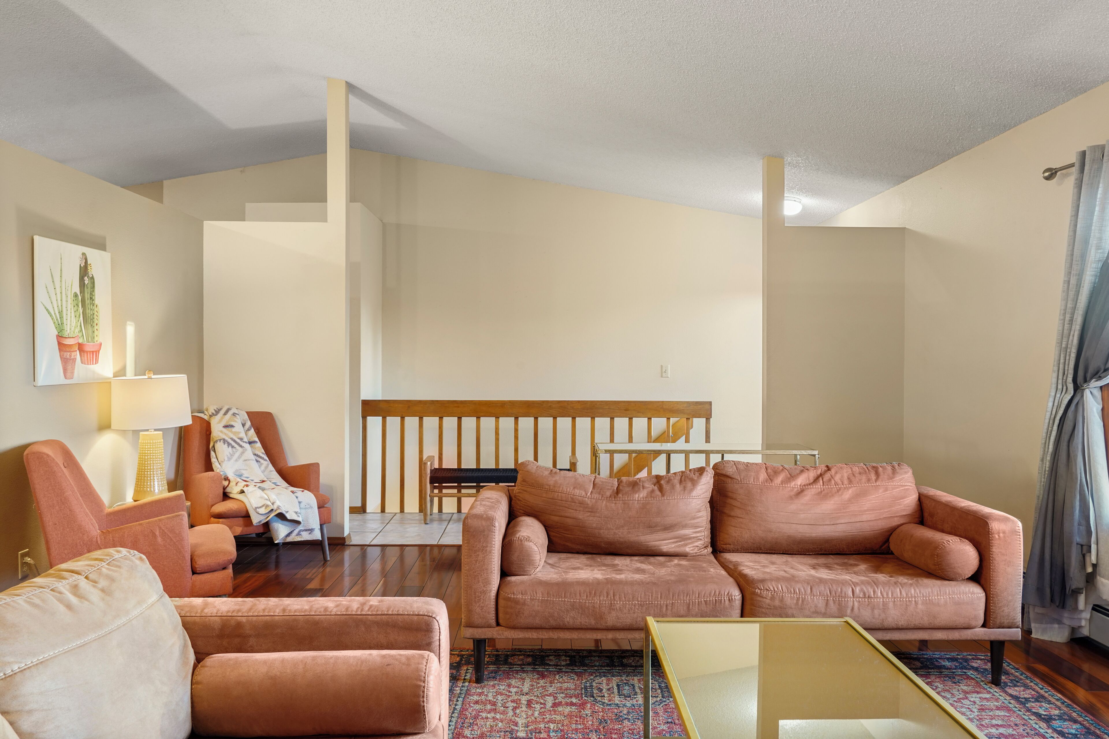 A living room with a sofa, armchairs, a coffee table, and a staircase leading to an upper level.